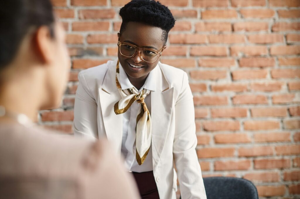 Happy black CEO talking to her coworker on a meeting in the office.